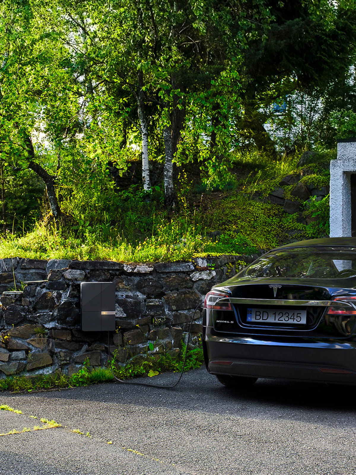 Andersen EV charger installed on natural stone wall connected to car outside garage